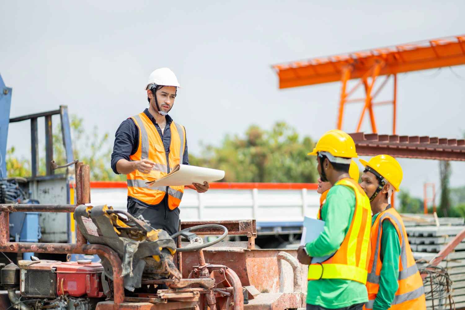 Engineer on construction site reviewing plans with workers